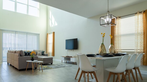 Uma sala de estar moderna com sofá, mesa de centro e área de jantar com cadeiras e mesa.