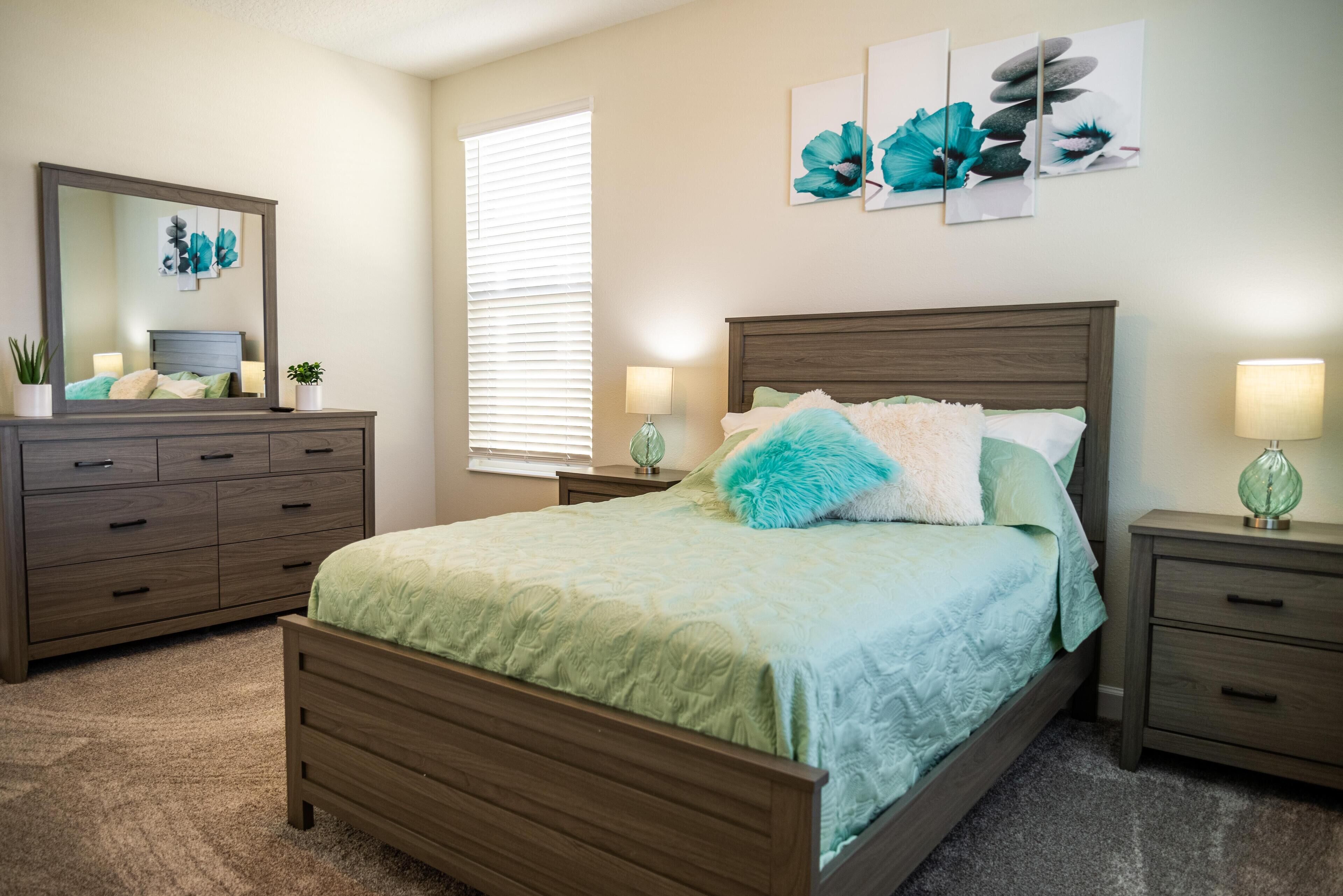 A bedroom with a bed, dresser, nightstands, and wall art.