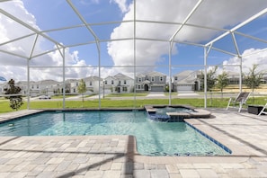 Piscina com ofurô, cercada por um terraço coberto e vista para edifícios residenciais.