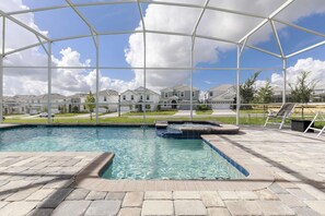 A swimming pool with a covered area, stone tiles, and a view of houses in the background. - Laguna Reef by Orlando Short Term (Davenport)