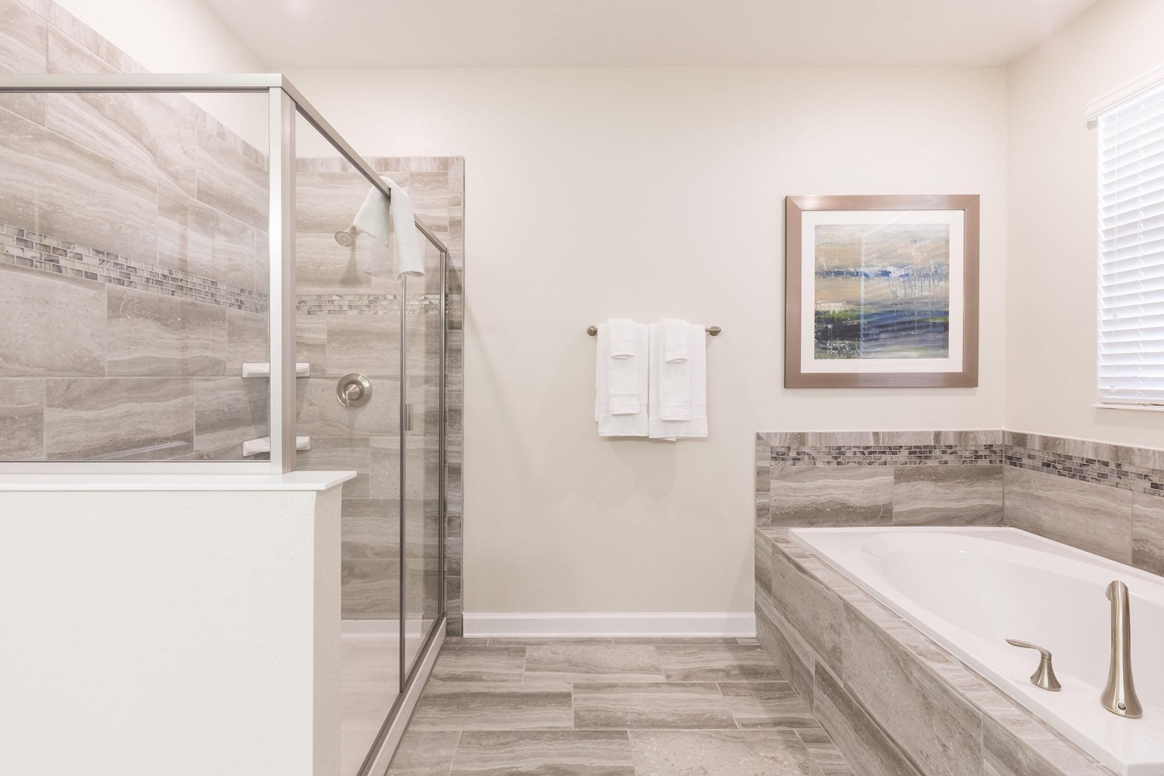 A modern bathroom with a glass-enclosed shower, a freestanding bathtub, and a tiled backsplash.