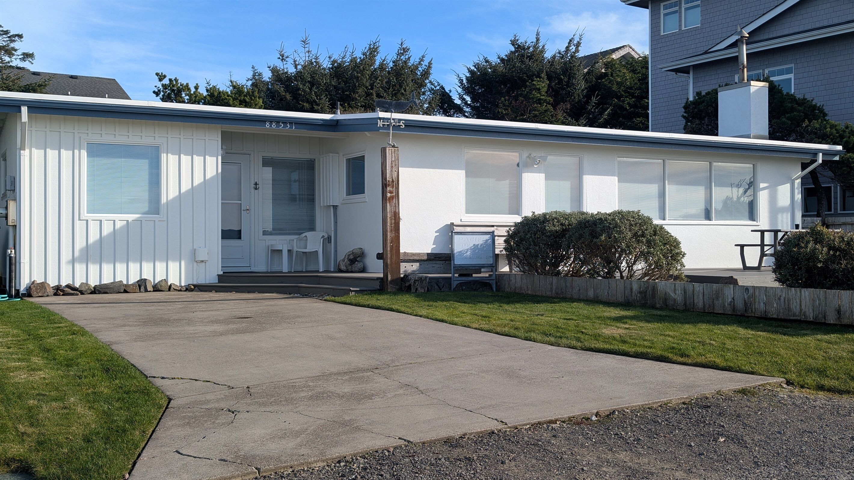 A single-story building with a white exterior, a covered front porch, and a small front yard.