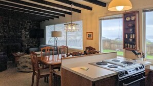 A kitchen with a central island, wooden chairs, a dining table, a stove, and a hanging light fixture. - Pacific Pearl at Heceta Beach  - dog friendly (Florence)