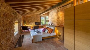 Ein gemütliches Schlafzimmer mit Bett, Schreibtisch und Fernseher, mit freiliegenden Holzbalken und Steinwänden.