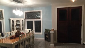 A dining area with a wooden table and white chairs, a white cabinet with glass doors, and a window with decorative metal bars. - Industrial chic farmhouse..... (Oshkosh)