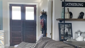 A living room with a sectional sofa, a wooden door, a shelf with various items, and a sign that says "GATHERING". - Industrial chic farmhouse..... (Oshkosh)