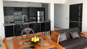 Una cocina moderna con armarios oscuros, un microondas integrado y un refrigerador de acero inoxidable.