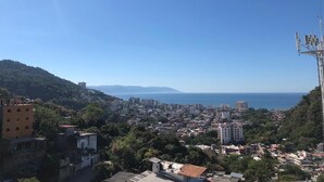 Un paisaje urbano costero con edificios, cielo despejado y una vista distante del mar.