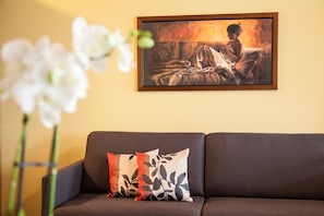 Um sofá marrom com almofadas estampadas e um quadro pendurado na parede.