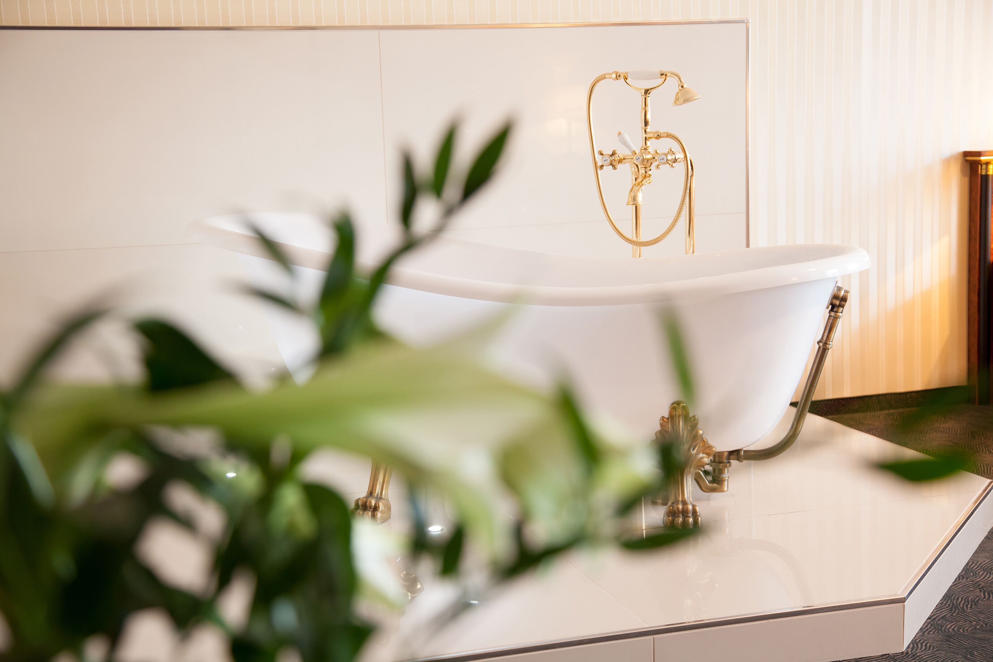 Una bañera con un grifo dorado y un número '6' decorativo en la pared de fondo.