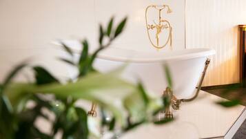 Una bañera con un grifo dorado y un número '6' decorativo en la pared de fondo.