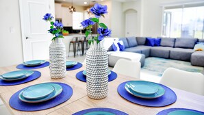 A dining table set with blue plates and a vase with blue flowers.