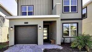 A modern two-story house with a garage, two windows on the upper floor, and a small porch area.
