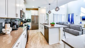 A modern kitchen with white cabinets, stainless steel appliances, and a central island.