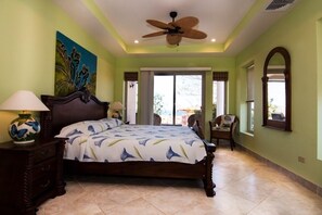 A bedroom with a bed, a ceiling fan, a nightstand, a chair, and a window.