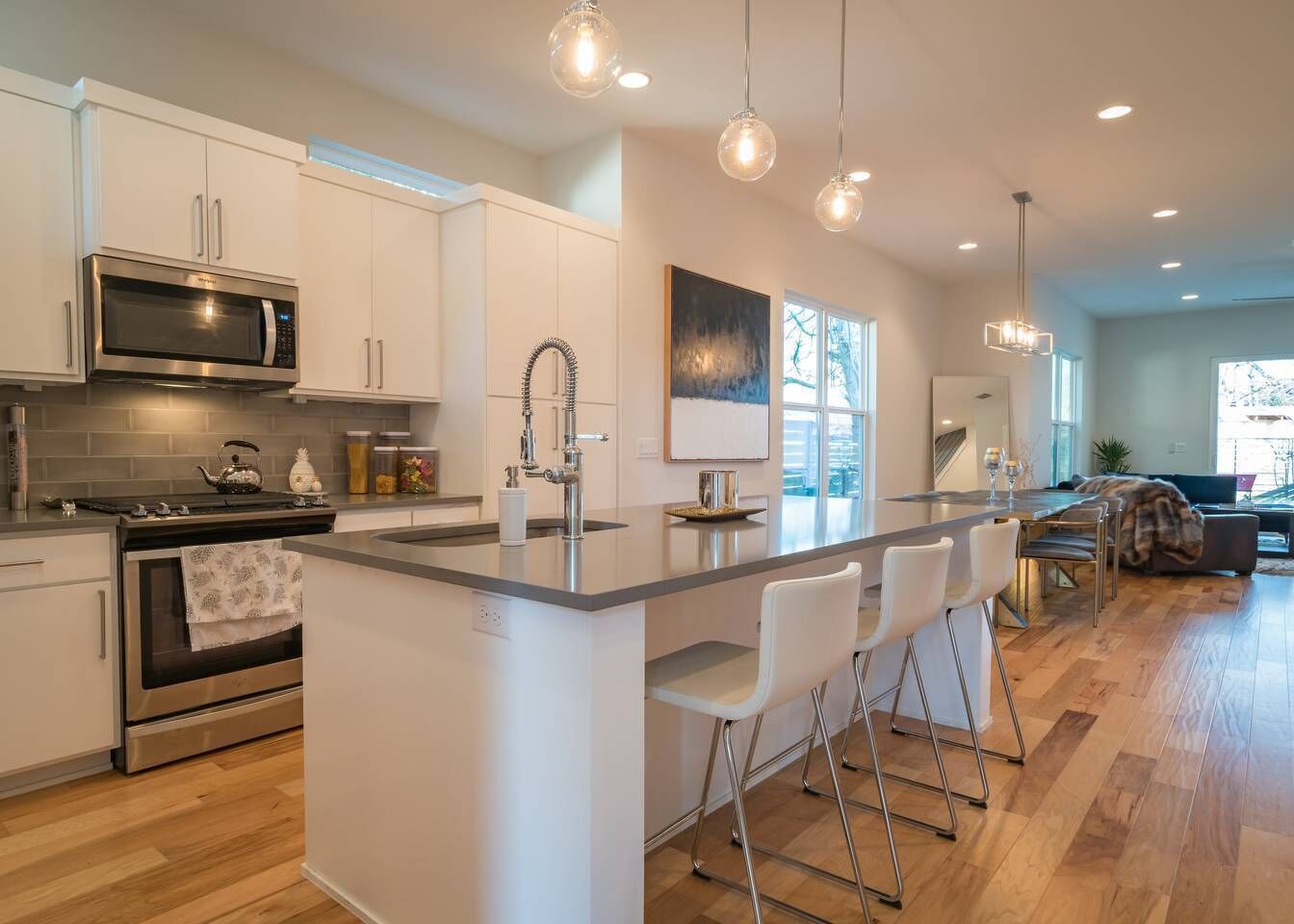A modern kitchen with a central island, stainless steel appliances, and pendant lighting.