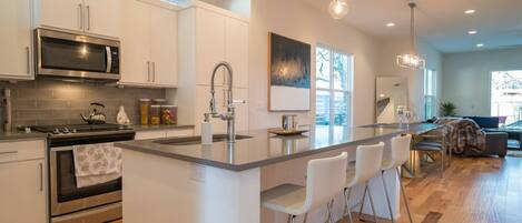 A modern kitchen with a central island, stainless steel appliances, and pendant lighting.