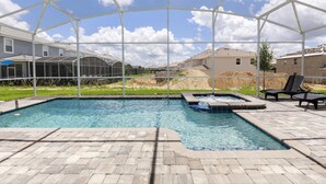 A swimming pool with a hot tub, surrounded by a covered patio area. - Tropical Escape by Orlando Short Term (Davenport)