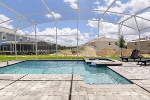 A swimming pool with a hot tub, surrounded by a covered patio area. - Tropical Escape by Orlando Short Term (Davenport)