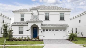 A two-story residential house with a blue front door, a garage, and a well-maintained lawn.