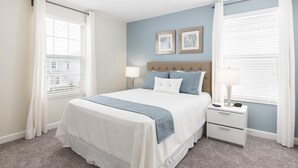A neatly arranged bedroom with a bed, bedside tables, and a nightstand. - Tropical Escape by Orlando Short Term (Davenport)