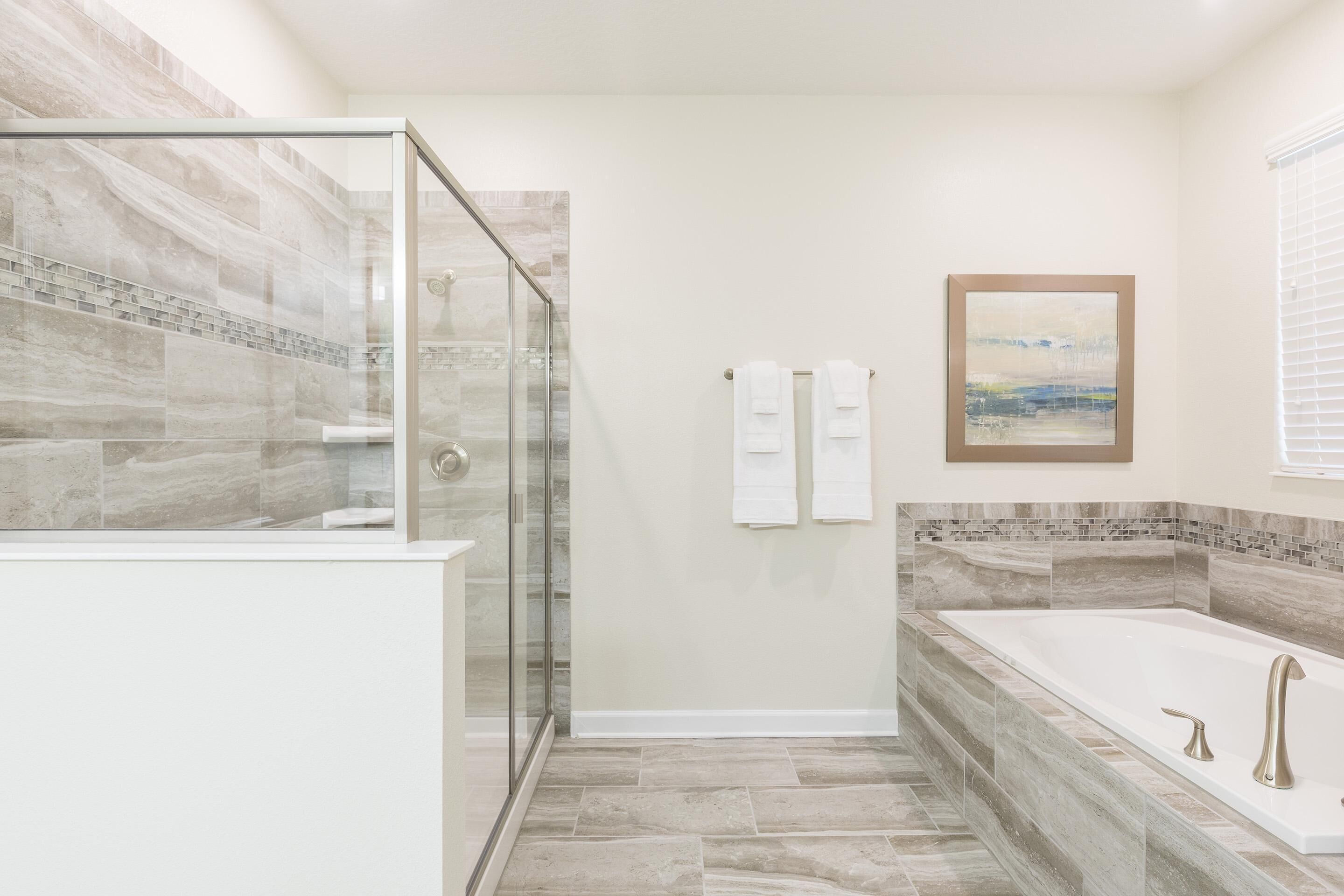 Un baño moderno con ducha de vidrio, una bañera independiente y piso de baldosas.