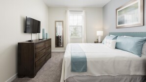 A bedroom with a bed, dresser, TV, and a window with blinds. - Tropical Escape by Orlando Short Term (Davenport)