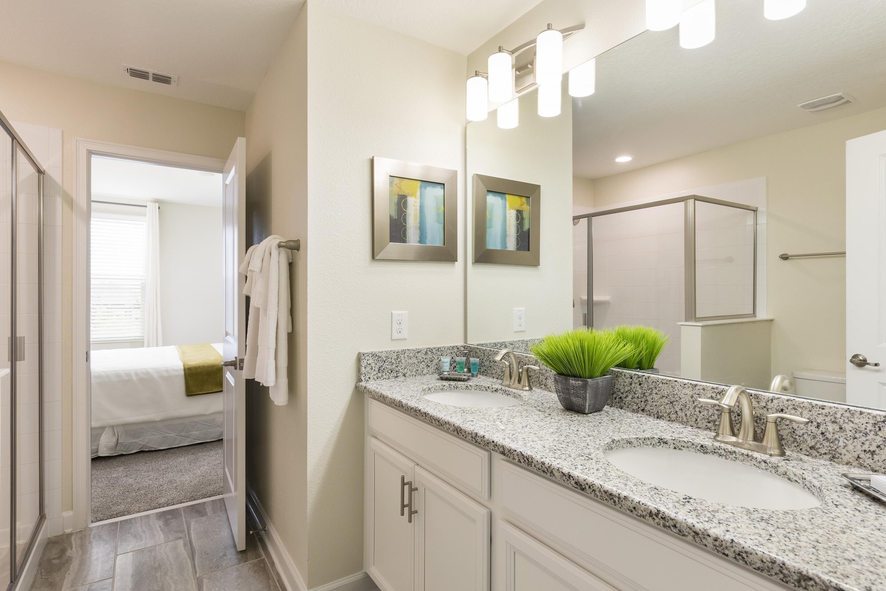 A bathroom with two sinks, a large mirror, and a shower area.