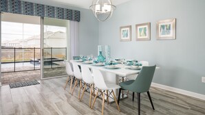 A dining area with a table set for four, white chairs, and a teal accent chair. - Tropical Escape by Orlando Short Term (Davenport)