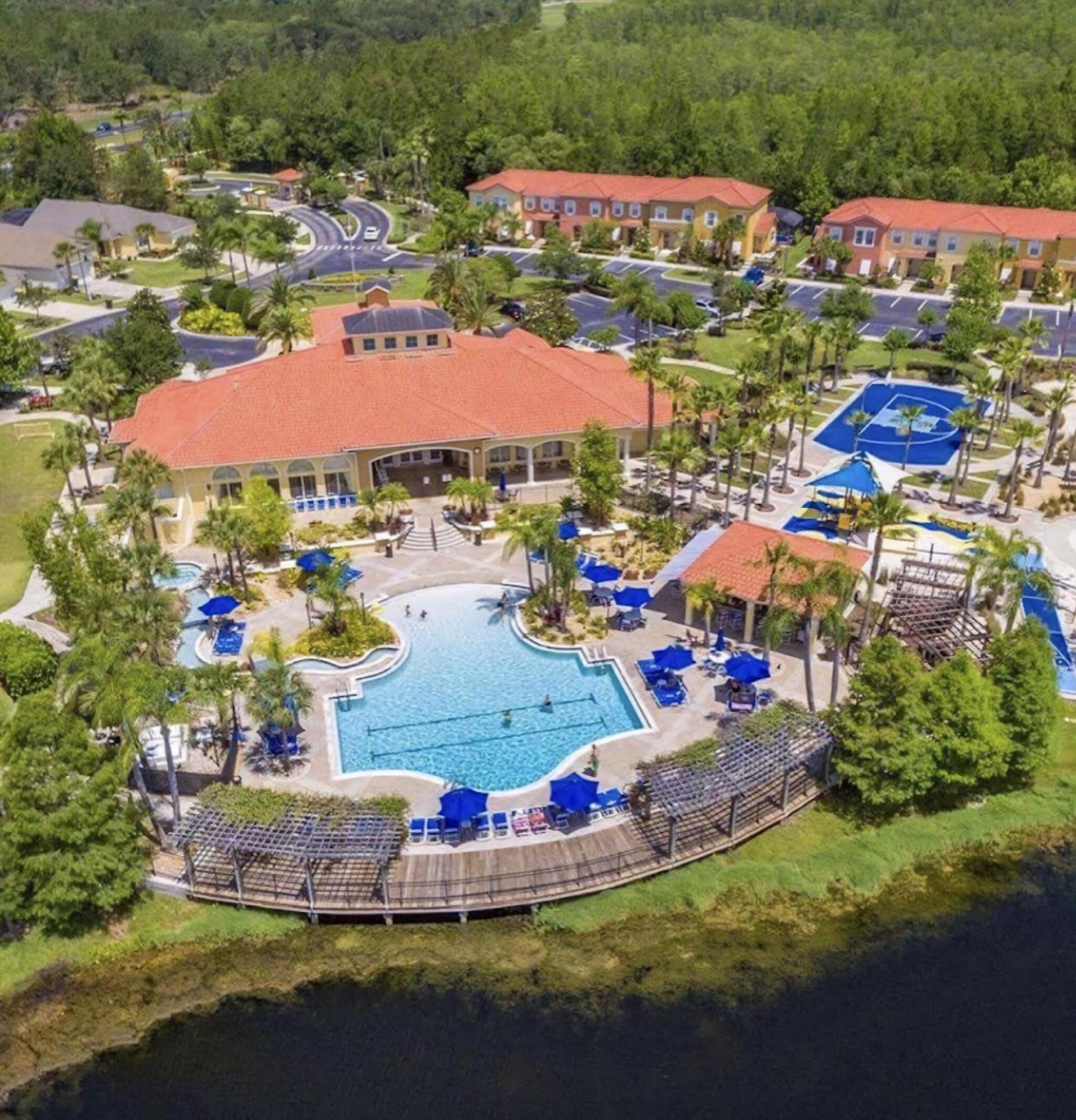 A resort with a central swimming pool, multiple tennis courts, and a variety of outdoor seating areas.