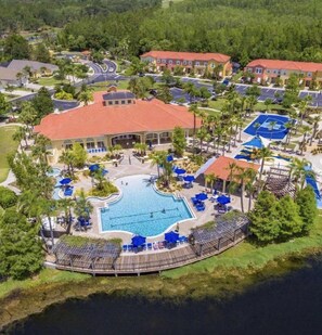 A resort with a central swimming pool, multiple tennis courts, and a variety of outdoor seating areas.