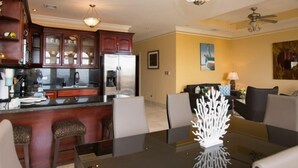 A modern kitchen with dark wooden cabinets, a stainless steel refrigerator, and a glass island. - Casa Q (Sardinal)