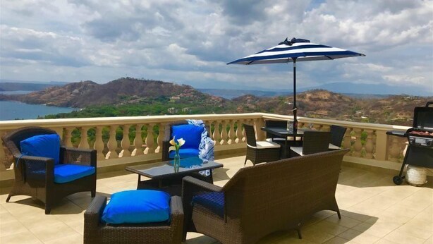 A balcony with wicker furniture, a table, and a grill. - Casa Q (Sardinal)