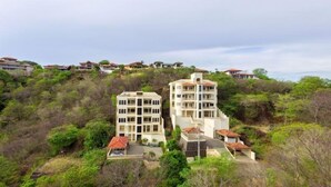 A hillside residential area with multiple multi-story buildings, each featuring balconies and a uniform architectural style. - Casa Q (Sardinal)