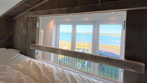A bedroom with a large window overlooking a coastal view. - Meeresblick " Fräulein Krabbe " Haus 3 WE 40 (Hohwacht)