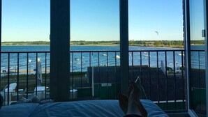 A room with a large window overlooking a body of water, a bed, and a chair. - Meeresblick " Fräulein Krabbe " Haus 3 WE 40 (Hohwacht)