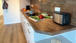 A modern kitchen with a wooden countertop, a toaster, and fresh vegetables. - Meeresblick " Fräulein Krabbe " Haus 3 WE 40 (Hohwacht)