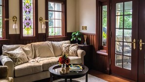 A cozy living room with a beige sofa, a round coffee table with a vase of flowers, and a large window with a view of greenery. - Mountain View Retreat (Fairfax)