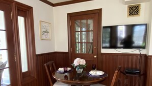 A dining room with a wooden table, chairs, a vase with flowers, and a television mounted on the wall. - Mountain View Retreat (Fairfax)