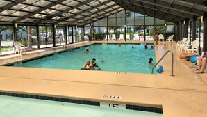 Una piscina interior con agua cristalina, un trampolín y techo cubierto.
