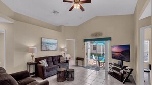 A spacious living room with a ceiling fan, a large flat-screen TV, a sofa, and a coffee table. - Canary Island by Orlando Short Term (Davenport)