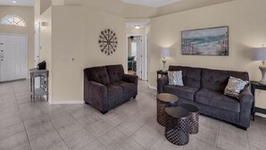 A spacious living room with two sofas, a coffee table, and a dartboard on the wall. - Canary Island by Orlando Short Term (Davenport)
