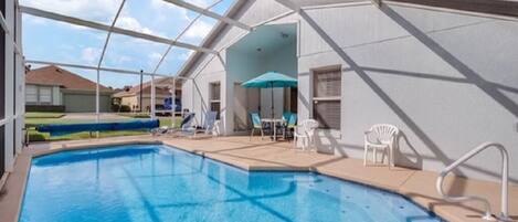 An indoor swimming pool with clear blue water, surrounded by white walls and a glass ceiling.