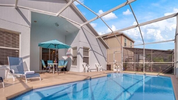 A swimming pool with lounge chairs and umbrellas, surrounded by a covered patio area. - Canary Island by Orlando Short Term (Davenport)