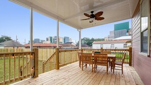 A covered outdoor deck with wooden furniture and a ceiling fan. - Rent My NOLA Jewel, Luxury Accommodations (New Orleans)