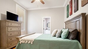 A bedroom with a bed, dresser, television, and framed pictures on the wall. - Rent My NOLA Jewel, Luxury Accommodations (New Orleans)