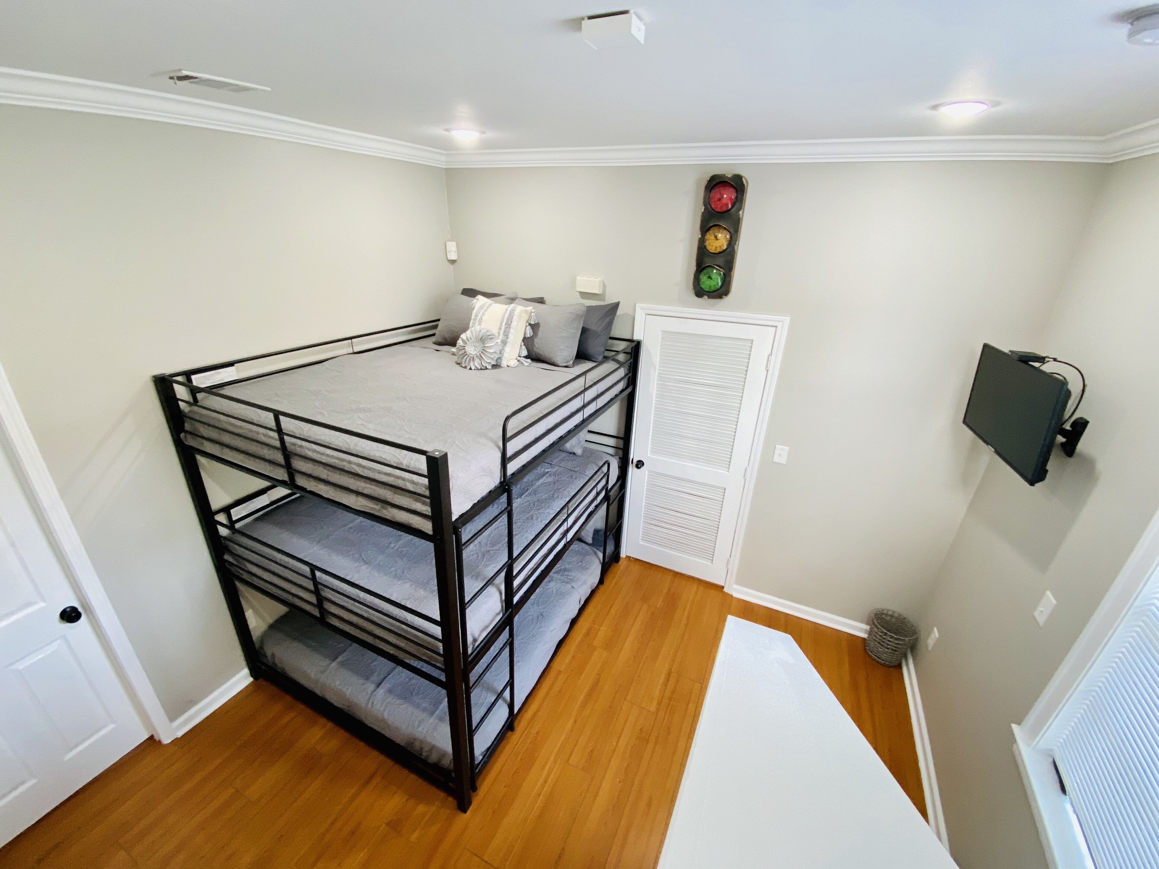 A room with a bunk bed, a door, a wall-mounted clock, and a radiator.
