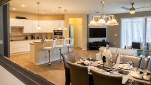 A modern kitchen with white cabinets, a central island, and pendant lighting. - Sunrise Valley Villa by Orlando Short Term (Kissimmee)