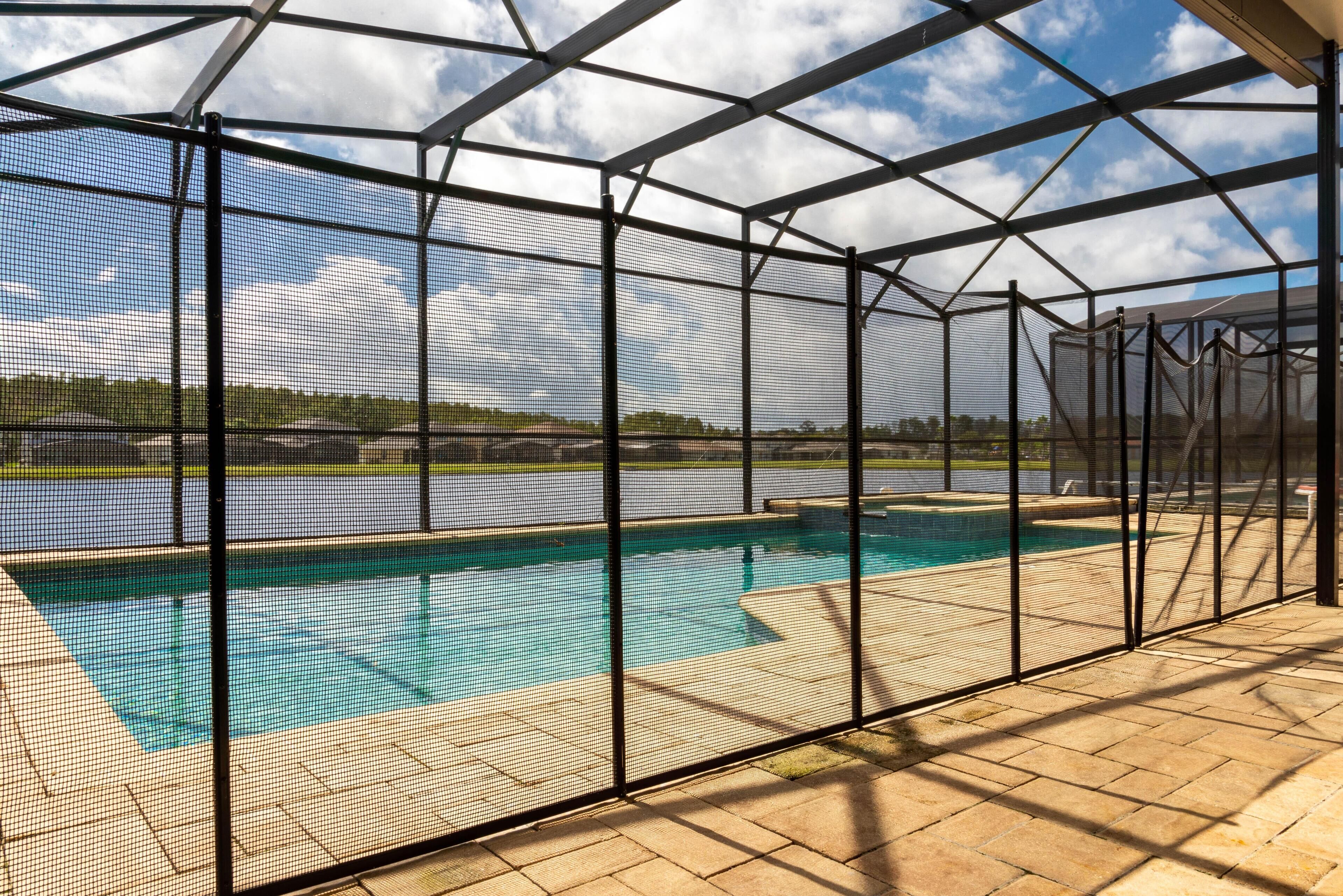 A covered outdoor swimming pool with a view of a lake and a clear sky.