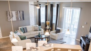 A modern kitchen with a built-in island, stainless steel appliances, and a dining area with a round table and chairs. - Sunrise Valley Villa by Orlando Short Term (Kissimmee)